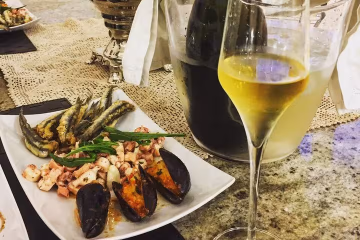 Gourmet seafood platter paired with white wine highlighting the culinary delights of extra virgin olive oil tours.
