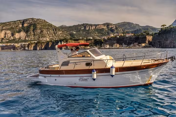 Typical Gozzo 850 boat cruising near Sorrento's scenic coastline on a private tour to Positano and Amalfi.