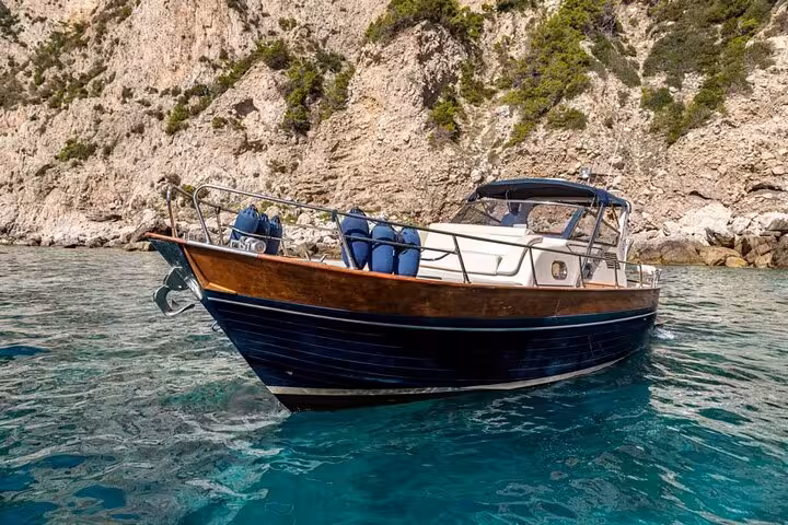 Docked Gozzo Apreamare 10 against Positano's rocky shores, offering a serene tour experience.