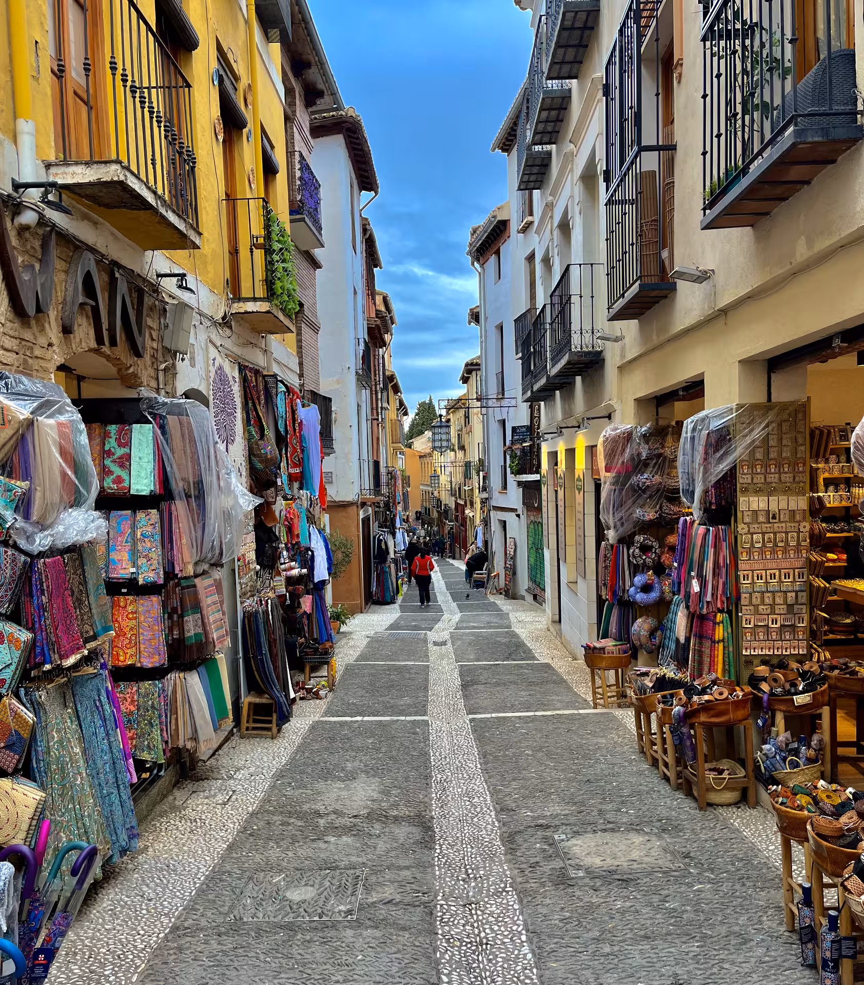 Granada bazaar street near Alhambra with colorful textiles and souvenirs on Encantos Locales + Alhambra tour