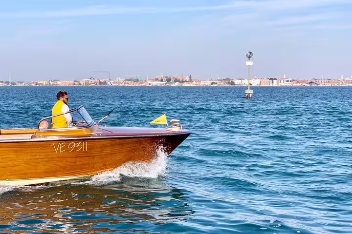 Wooden motorboat cruising on the Grand Canal during the Murano boat tour from Piazzale Roma, Venice.