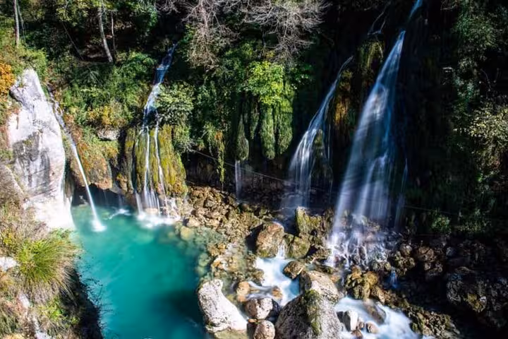Scenic waterfall cascading into turquoise pool surrounded by lush greenery in the Grand Canyon of Europe.
