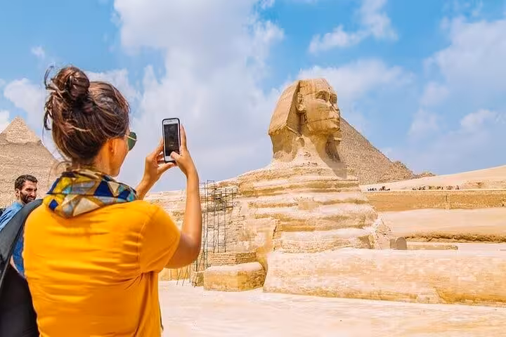 Tourist photographing the Great Sphinx and Giza Pyramids on Cairo day trip by bus from Sharm El Sheikh
