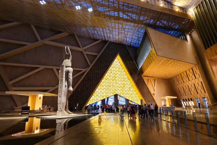 Grand Egyptian Museum Cairo main hall with pyramid entrance and statues, QR ticket entry and optional transfer