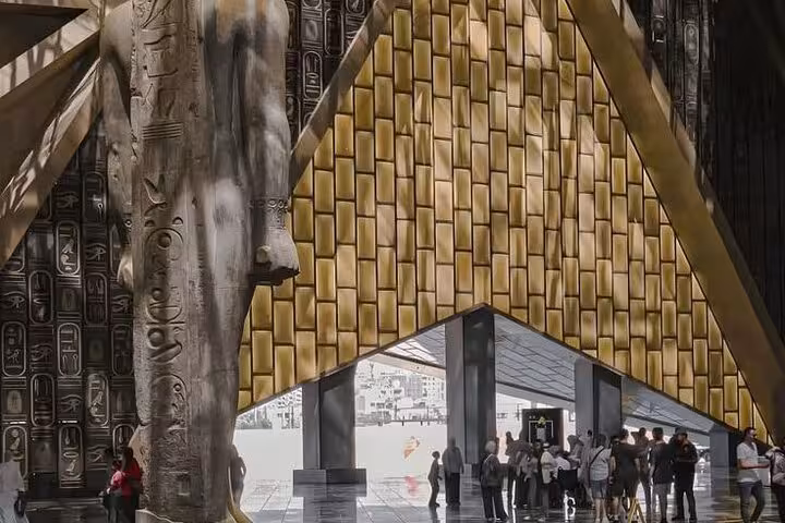 Grand Egyptian Museum entrance with colossal statue and gold facade on guided female Egyptologist Cairo tour