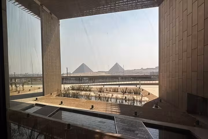 Grand Egyptian Museum window framing Giza Pyramids view, elegant full-day Cairo tour highlight