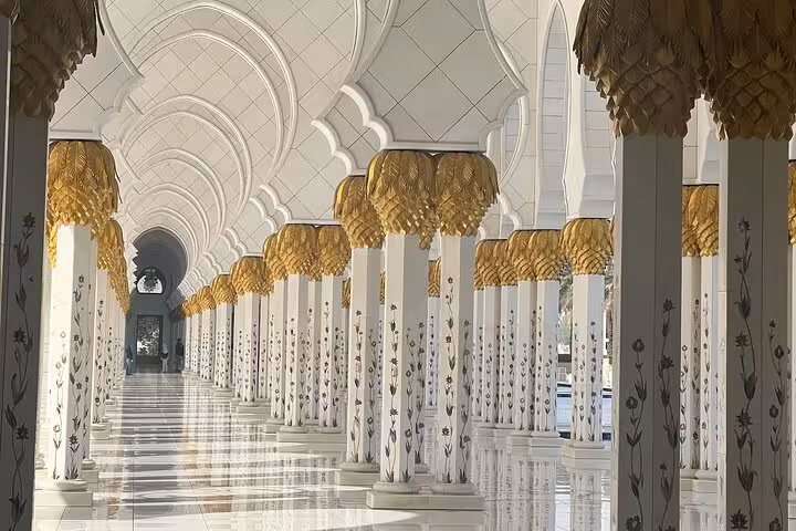Grand Mosque colonnade with floral columns and golden capitals on Dubai to Abu Dhabi multi day tour