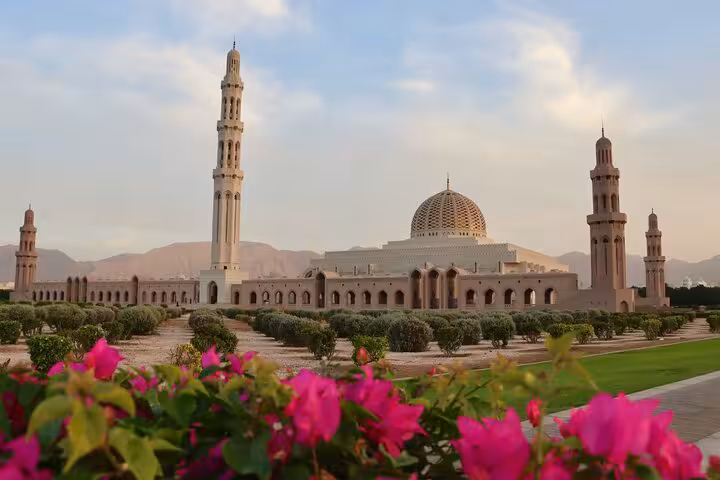 Grand Mosque in Muscat with domes, minarets and flowering gardens at sunset, a highlight of Half-Day Muscat City Tour