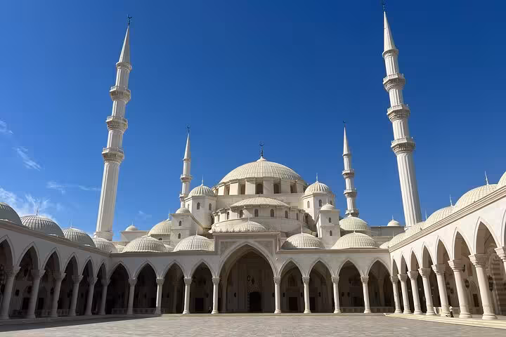Grand white mosque courtyard with domes and minarets, key UAE cultural landmark on Emirates tours
