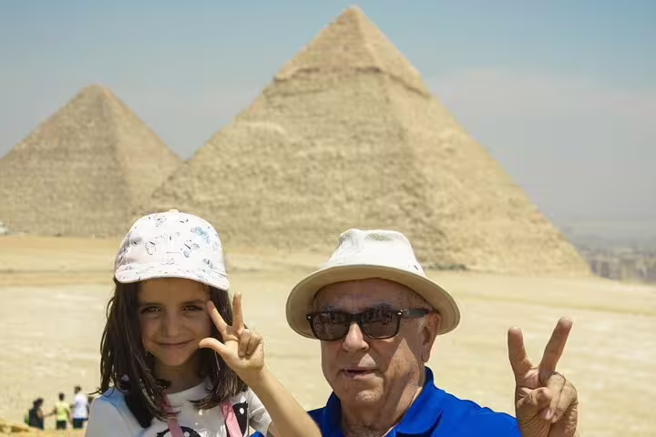 Grandfather and child making peace signs with Giza Pyramids behind on a 2-day private Cairo guided tour