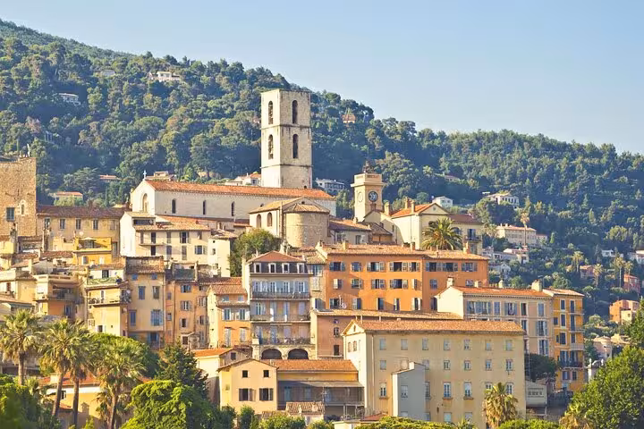 Charming hillside view of Grasse, showcasing its historic architecture and lush greenery on a sunny day.