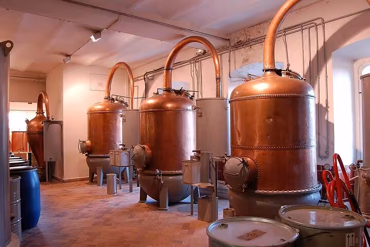 Interior view of a Grasse perfume factory with copper distillation tanks, showcasing traditional fragrance production methods.