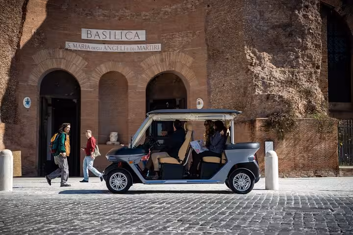 Tourists exploring the historic Basilica di Santa Maria degli Angeli in Rome via eco-friendly vehicle on The Great Beauty tour.