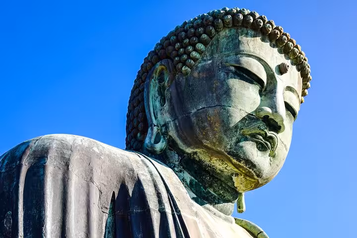 Close-up of the Great Buddha statue under a clear blue sky in Kamakura, a highlight of the Tokyo to Kamakura tour.