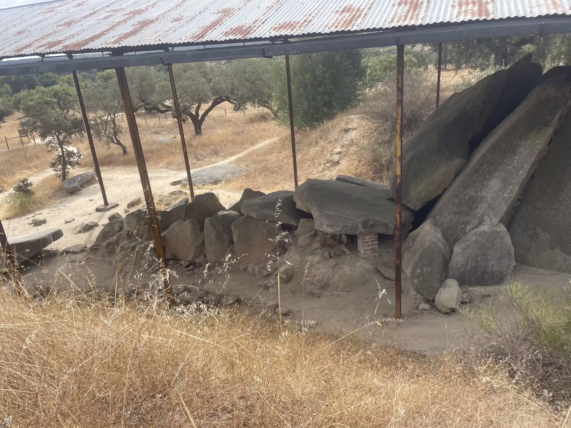Covered ancient stones of the Great Dolmen of Zambujeiro surrounded by dry landscape in Évora.