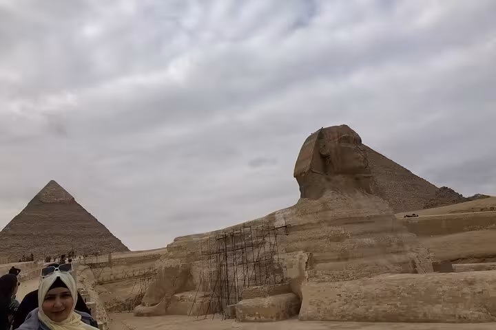 Great Sphinx of Giza with pyramids under cloudy sky, stop on a private Giza tour with camel ride and lunch