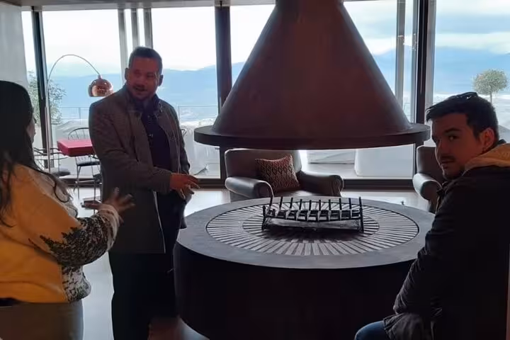 Travelers gather by a modern fireplace with sea views, part of Greece Wine Roads Athens to Santorini tour