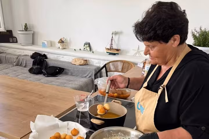 Local chef frying Greek loukoumades during the small group Mykonian cooking class experience in Mykonos