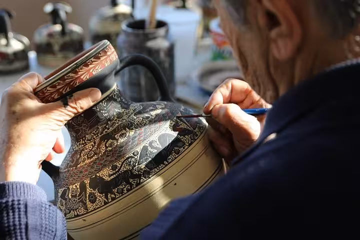 Artisan hand-painting a Greek ceramic vase during pottery workshop on Corinth Canal day trip from Athens
