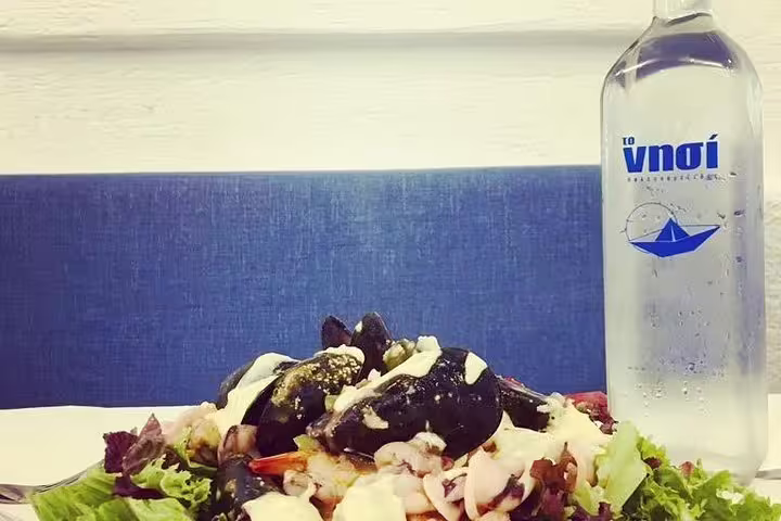 Fresh Greek salad with local ingredients and bottled water on a taverna table, ideal with grilled meat dinner