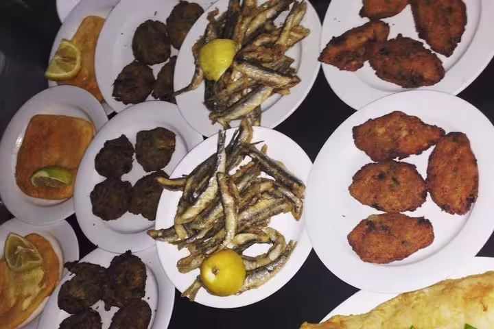 Greek taverna grilled plates with fried fish, meat patties and lemon, part of a local restaurant food tour
