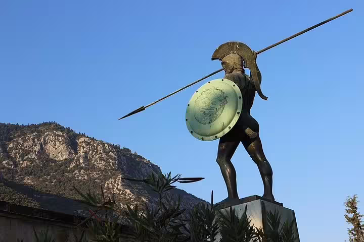 Statue of a Greek warrior with spear and shield against a backdrop of rocky mountains near Meteora.