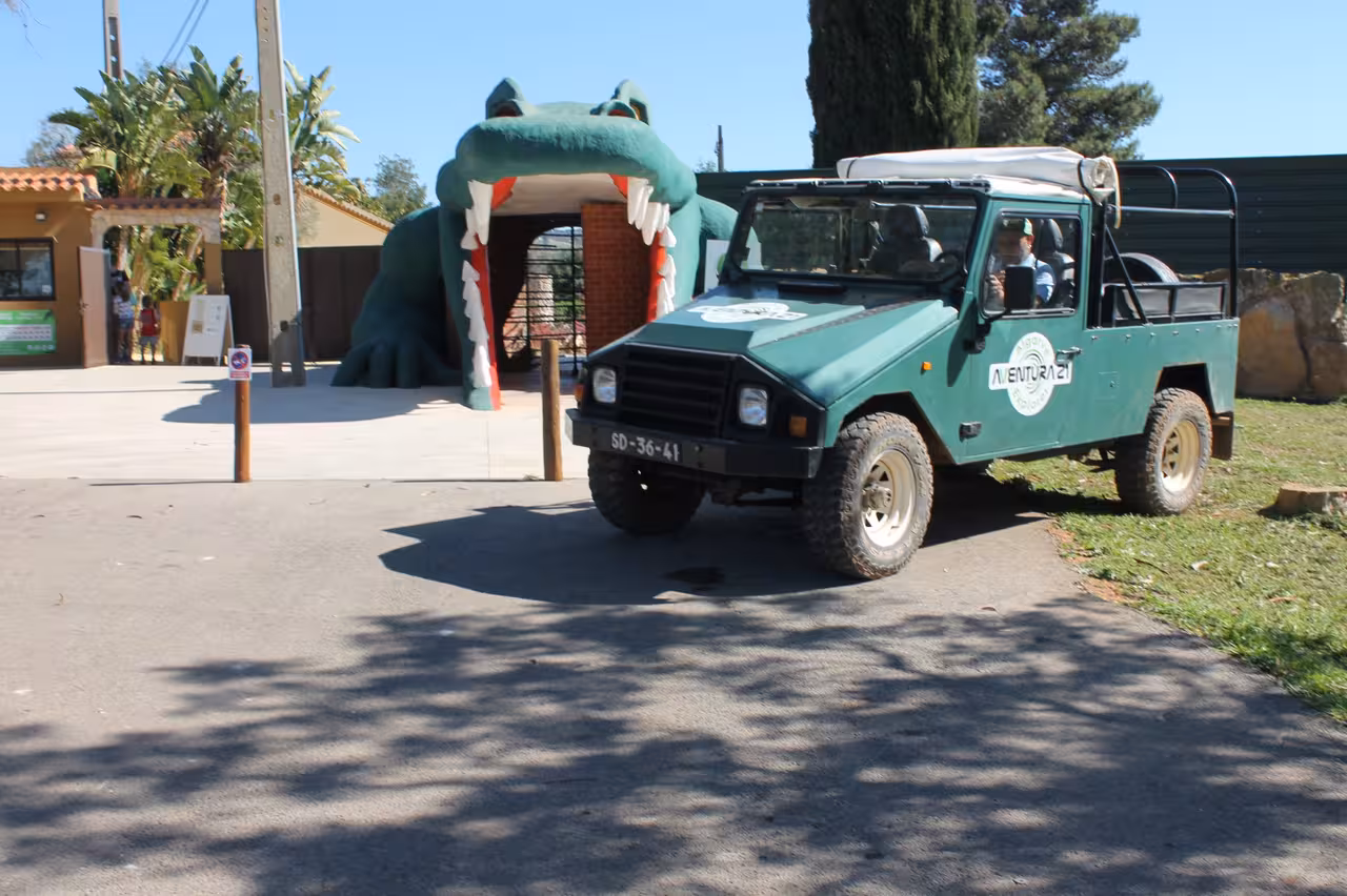 Green 4x4 Jeep Zoofari vehicle parked at zoo entrance with giant crocodile gate, ready for safari tour