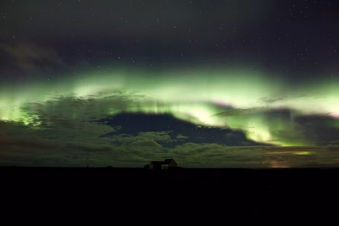 Green Northern Lights over a rural horizon under starry skies, perfect aurora and stargazing tour photo