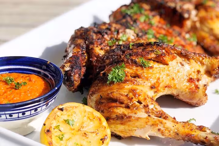 Grilled chicken with spices and lemon served with a side of red pepper sauce on the Lisbon food tour.