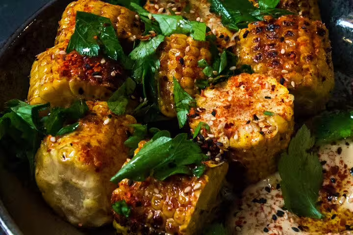 Grilled corn with spices and fresh herbs served as a savory accompaniment during a fortified wine tasting experience.