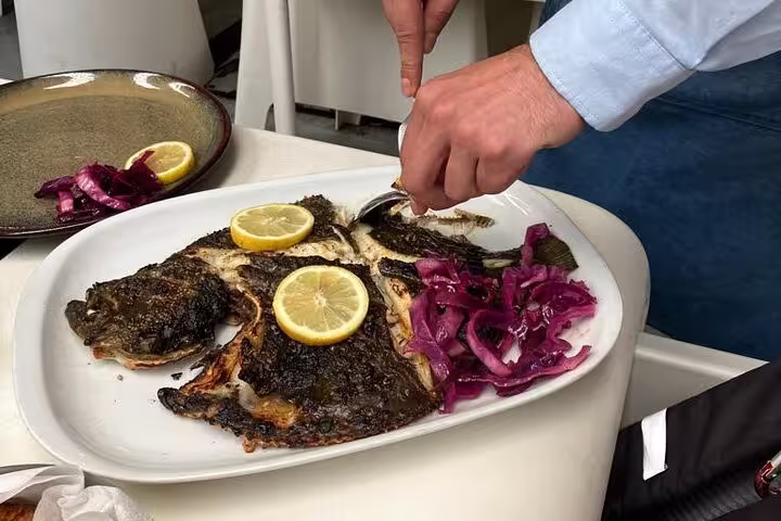 Freshly grilled fish garnished with lemon and purple onions, served during Porto Fish Tour Private Experience.
