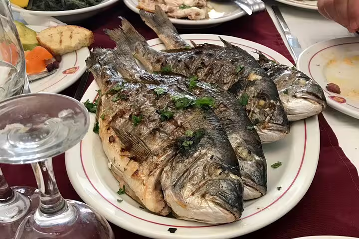 Grilled whole sea bream on a tavern table, perfect food pairing on Nafplio wine tasting tour via Corinth Canal