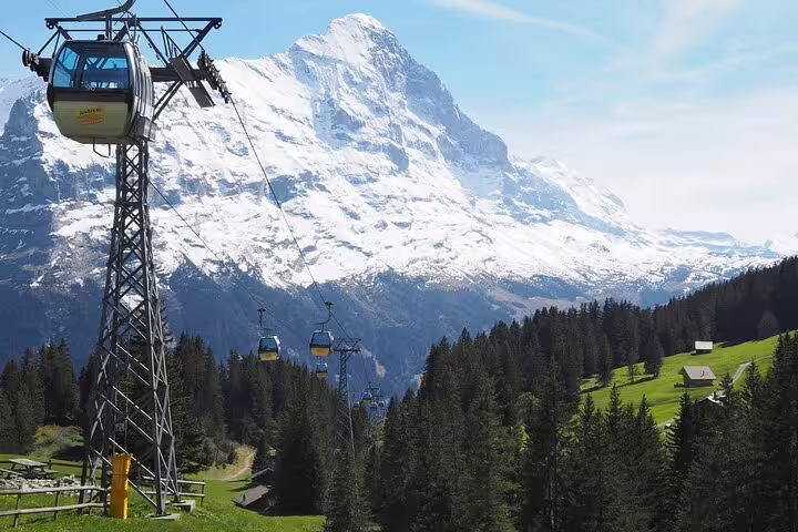 Cable cars ascend towards Grindelwald with the majestic snow-capped Eiger in the background.
