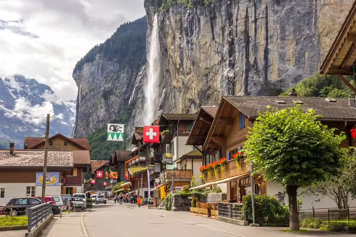 Quaint Swiss village street with traditional chalets and stunning waterfall view in Grindelwald, Switzerland.