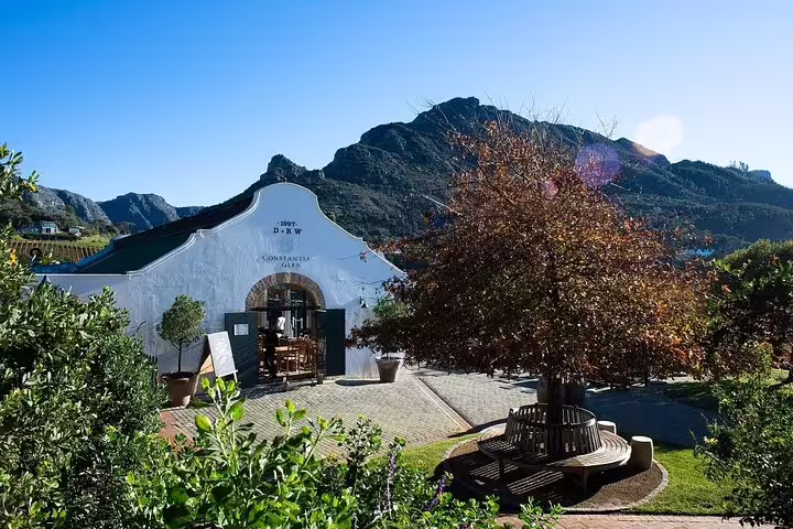 Historic white gabled building at Groot Constantia, surrounded by lush greenery and mountain views.