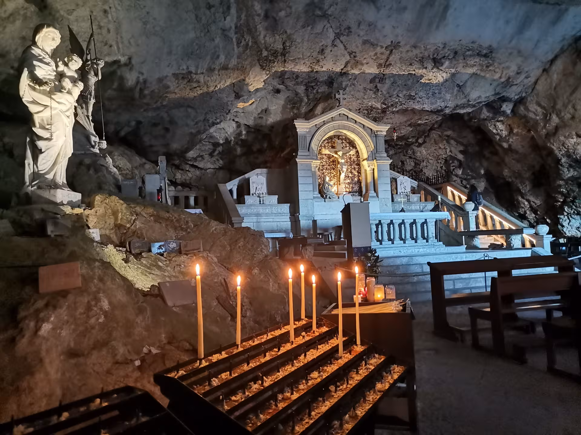 Candlelit grotto shrine with altar inside the Grotte Sainte-Madeleine cave, highlight of the sacred hike tour