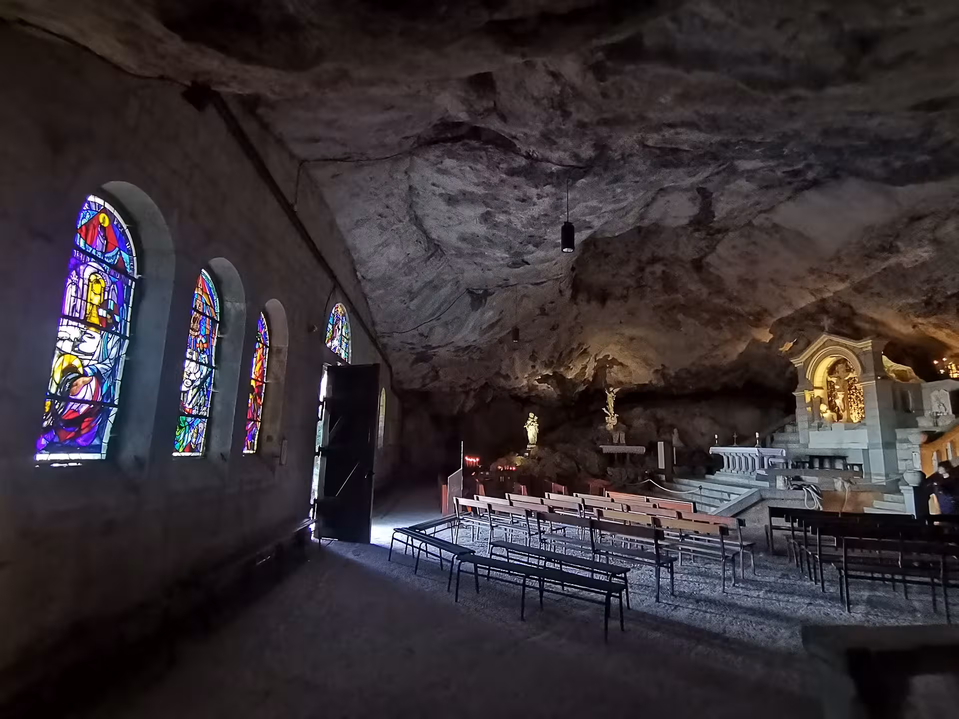 Stained-glass windows and chapel seating inside Grotte Sainte-Madeleine on a sacred guided hike in France
