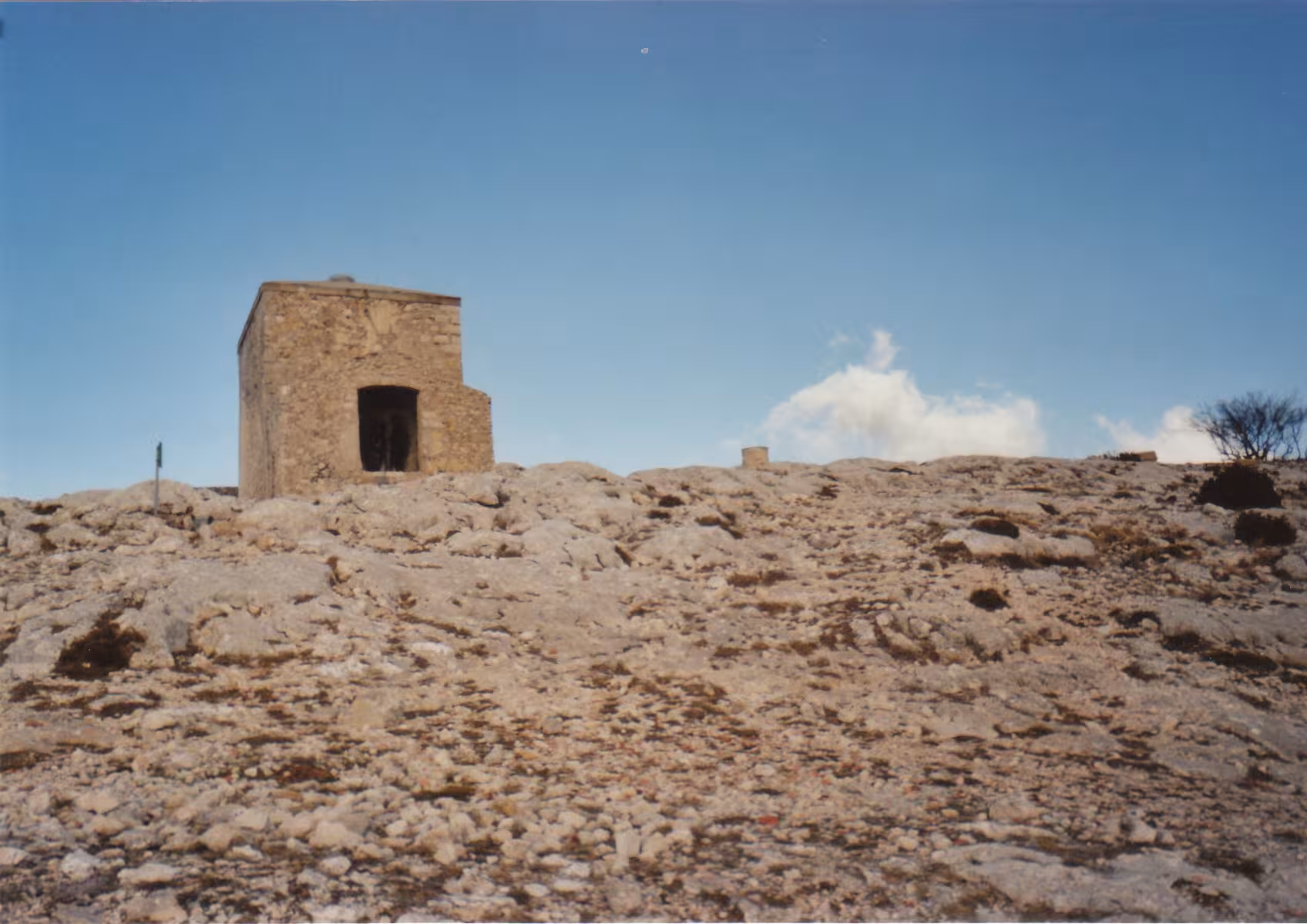 Rocky plateau with small stone shelter under blue sky on the sacred hike to Grotte Sainte-Madeleine
