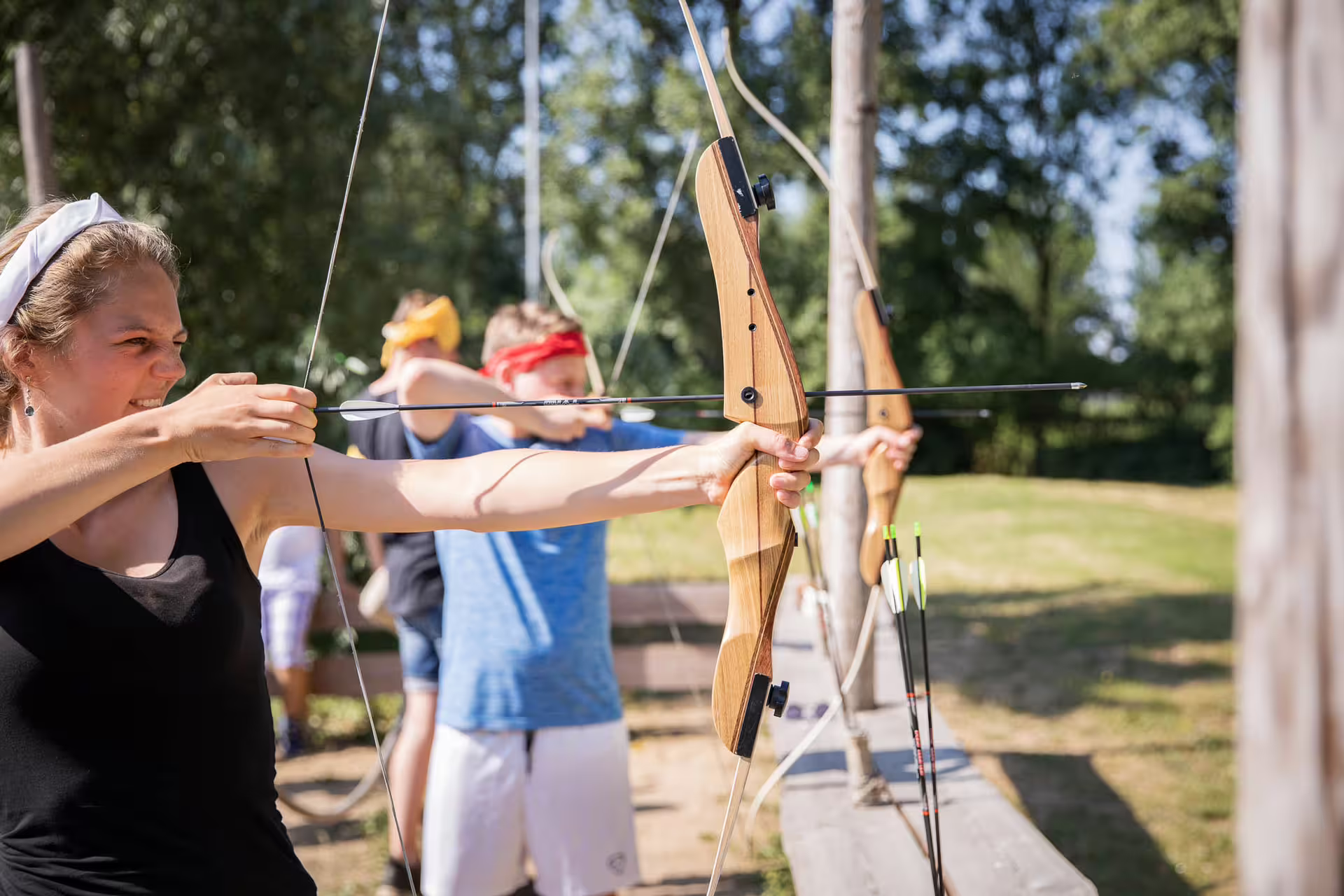 Group archery lesson in Weesp with adults drawing recurve bows on a sunny outdoor shooting line