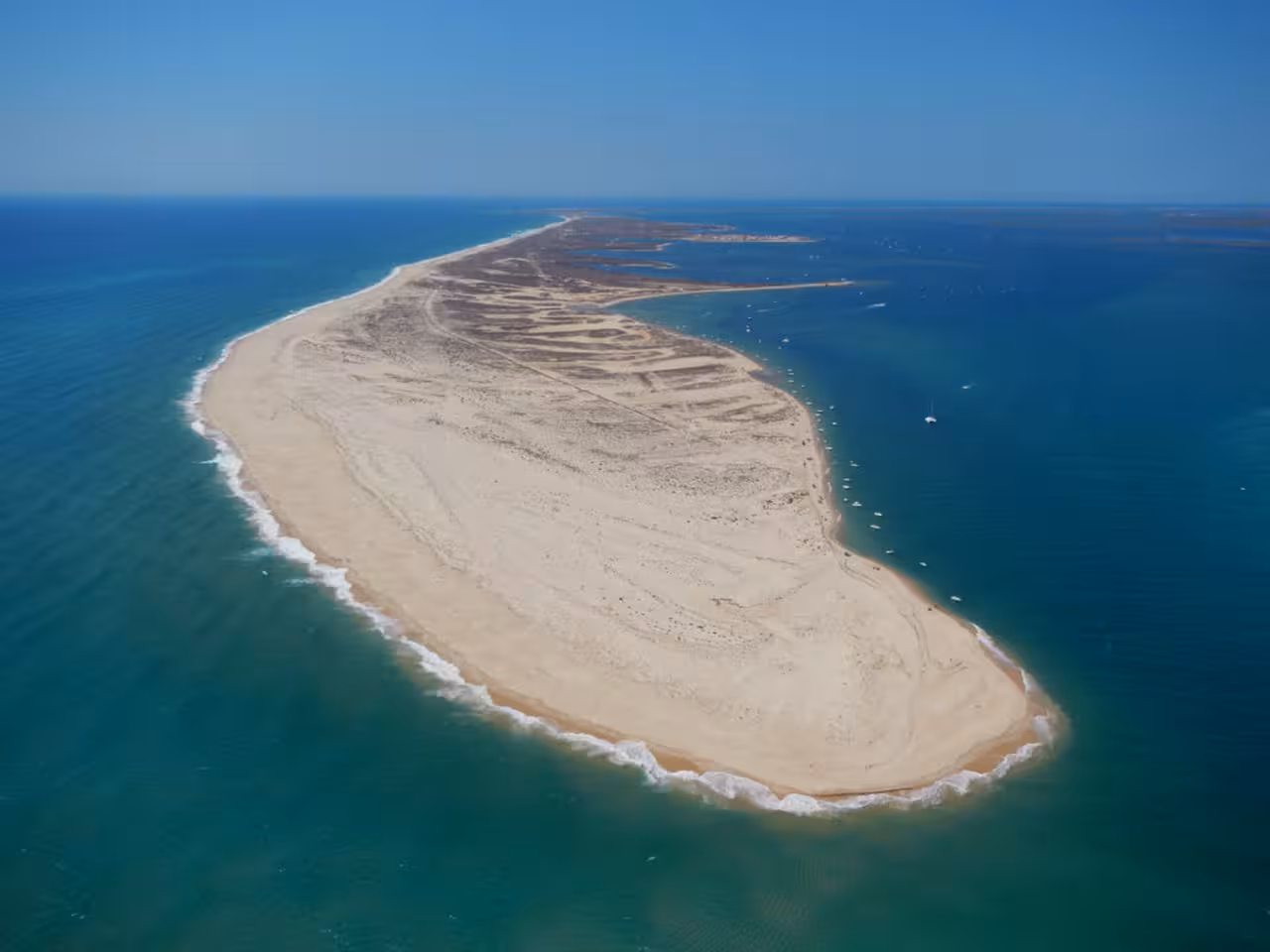 Aerial view of a sandy peninsula and turquoise sea, scenic coastal stop on a group cruise excursion