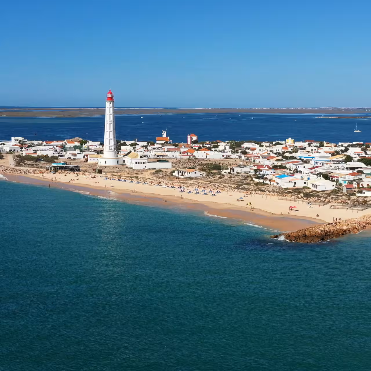 Aerial view of coastal town lighthouse and sandy beach, perfect for group cruise sightseeing and sea views
