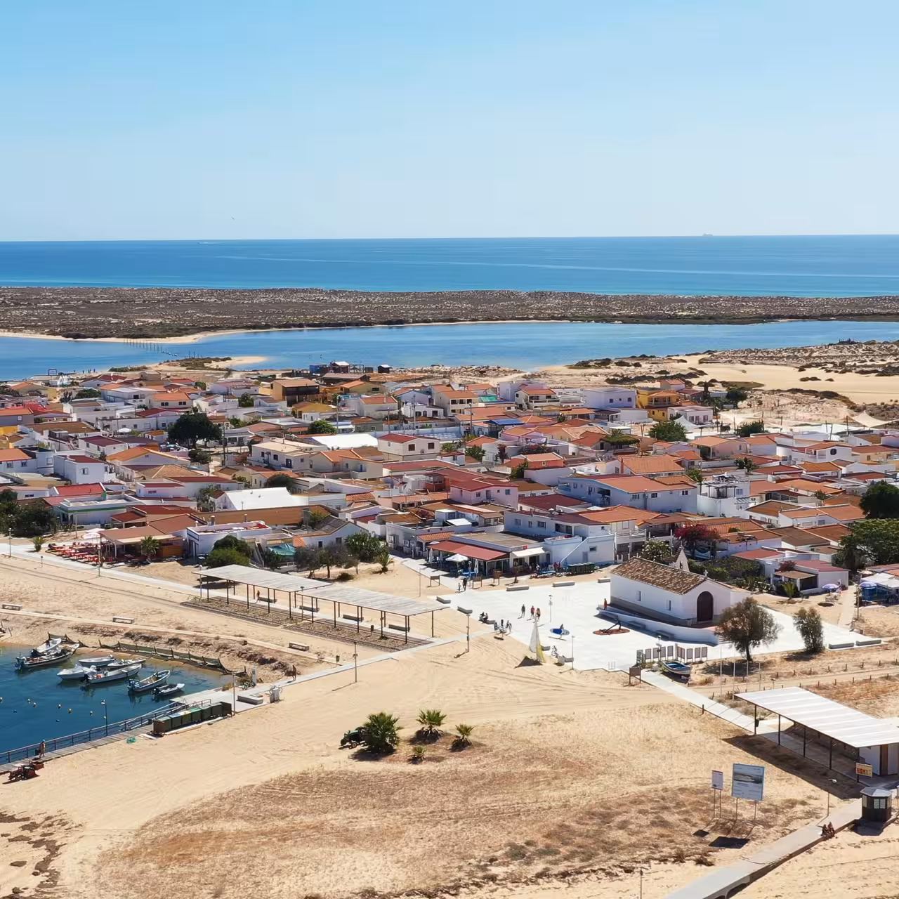 Panoramic coastal village by lagoon and ocean, ideal stop on group cruise with scenic shoreline and harbor views