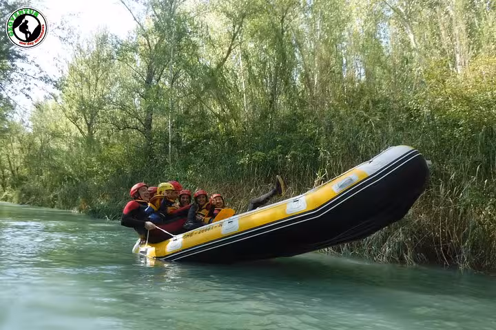 Group rafting on a calm river in Teruel, Spain, paddling an inflatable raft through lush forest scenery