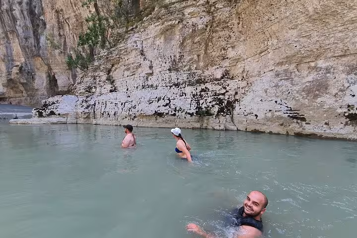 Group swimming in the refreshing waters of Osum Canyon, Albania, surrounded by dramatic rock formations.