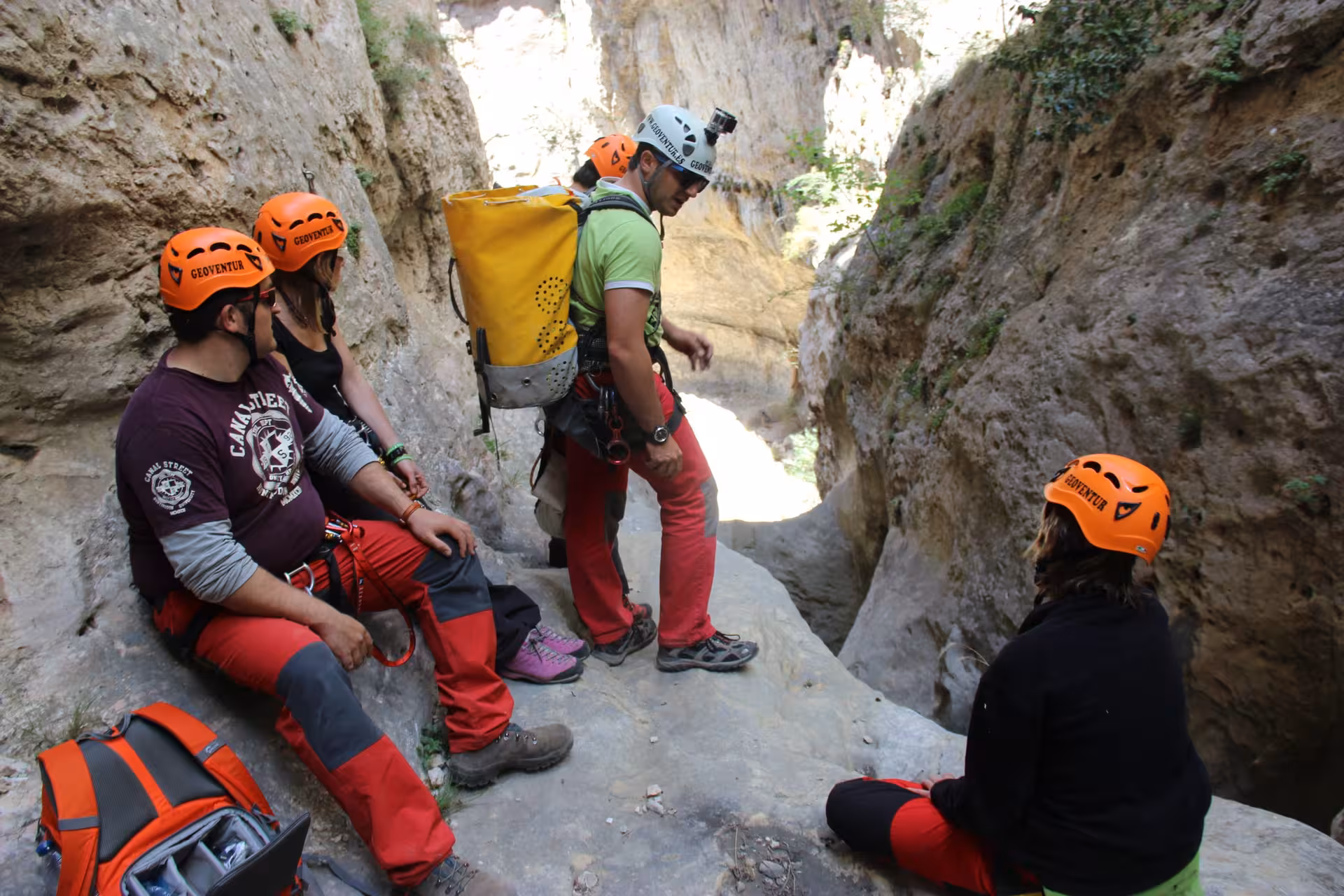 Grupo con cascos y arneses descansa en una repisa del barranco seco de Aliaga, Teruel, antes del rápel