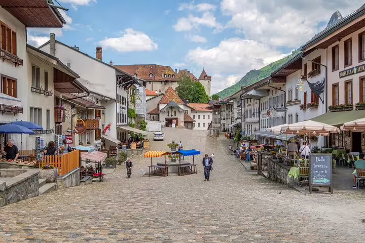 Charming cobblestone street in Gruyères lined with cafes and historic buildings ideal for a magical tasting tour.