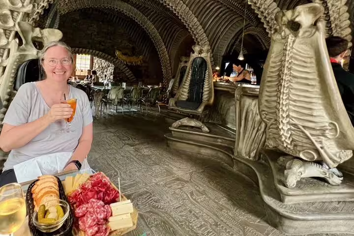 Visitor enjoying a drink and charcuterie at the H.R. Giger Bar in Gruyères with its iconic alien-themed interior.
