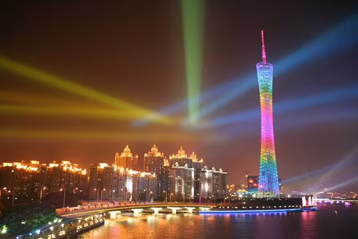 Vibrant night scene of the Canton Tower lit with colorful lights alongside the Pearl River, enhancing Guangzhou's skyline.