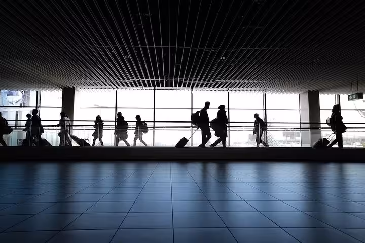 Travelers with luggage walking through Guarulhos Airport terminal for private transfer to São Paulo hotels.