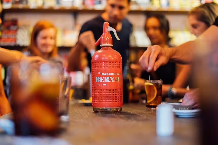 Guests enjoy a social tapas and wine experience around a table with a vintage beverage siphon centerpiece.